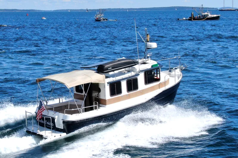 Slide: The Image of 2012 Ranger Tugs R-27 cruising on open blue water with other boats in the background. - 1