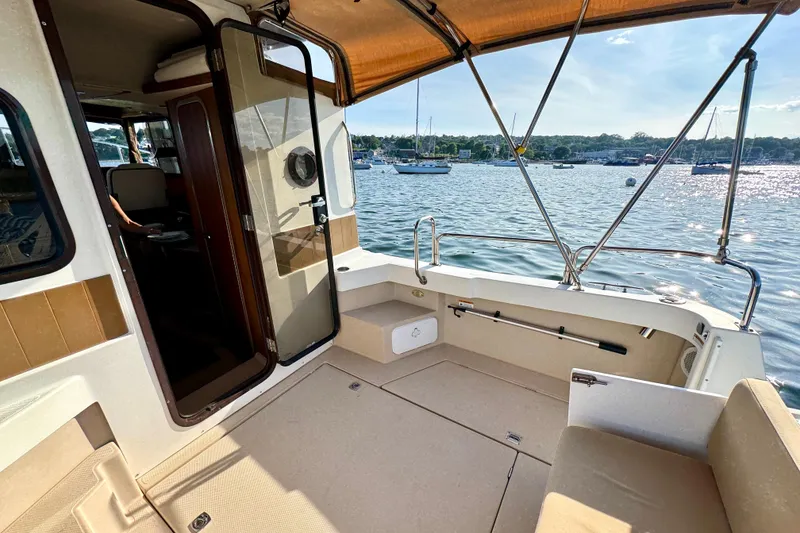 Slide: The Image of 2012 Ranger 27 boat interior with open deck, overlooking serene waters and moored sailboats. - 15