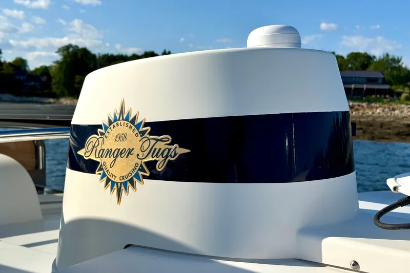 Slide: The Image of Ranger Tugs logo on a 2012 Ranger 27 boat, with scenic water and trees in the background. - 17