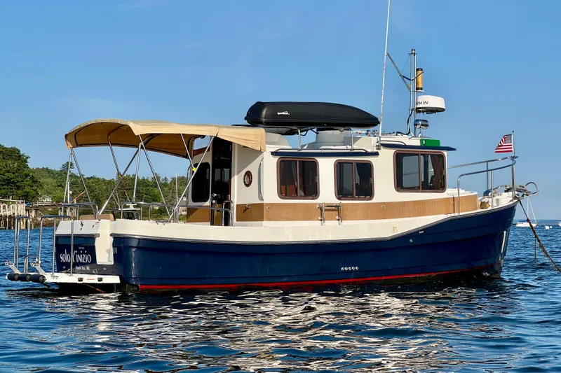 Slide: The Image of 2012 Ranger 27 boat on water with canopy and American flag. - 2