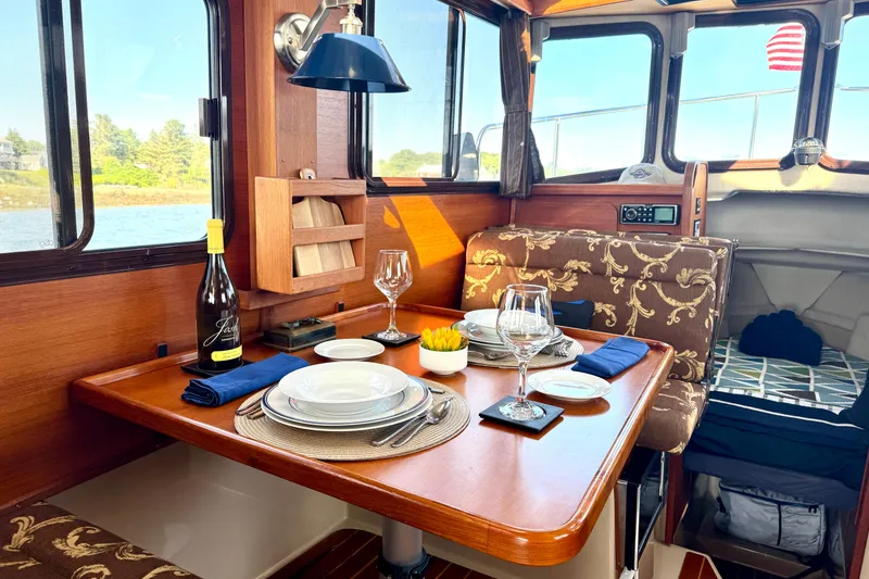 Slide: The Image of Elegant dining setup inside a 2012 Ranger 27 boat, featuring wine and tableware. - 26