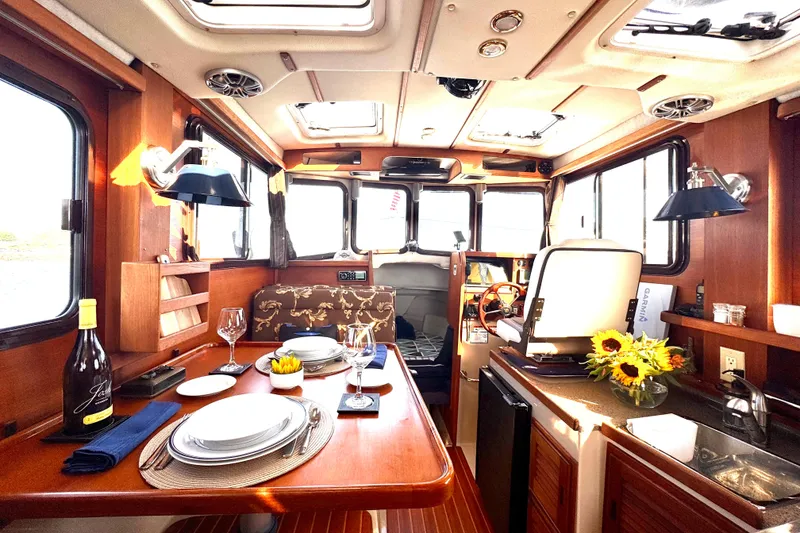 Slide: The Image of Luxurious 2012 Ranger 27 boat interior with dining setup and sunlit cabin. - 27