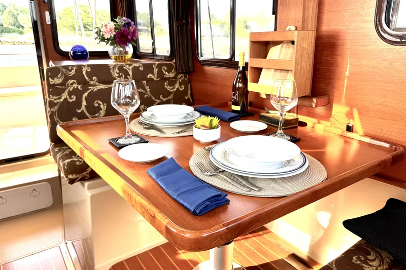 Slide: The Image of Elegant dining setup inside a 2012 Ranger 27 boat, featuring wine glasses and floral decor. - 28
