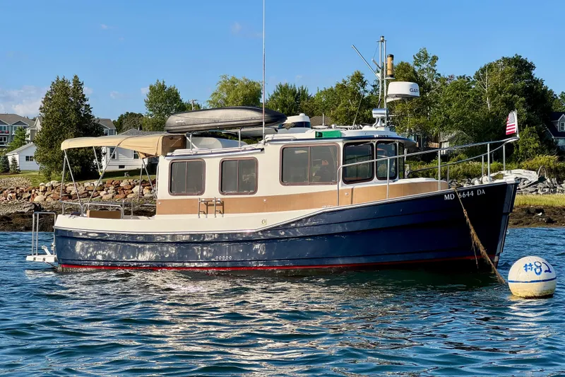 Slide: The Image of 2012 Ranger 27 boat anchored near shoreline with trees and houses in the background. - 3