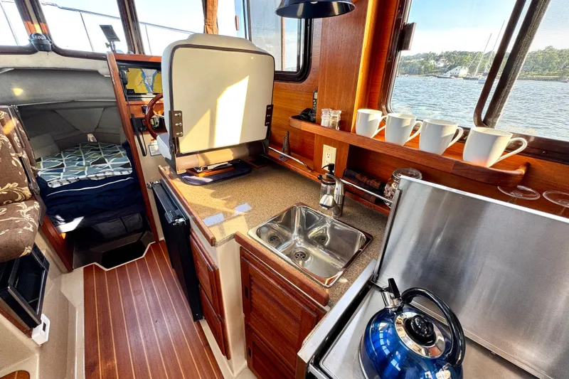 Slide: The Image of Cozy 2012 Ranger 27 boat interior with kitchenette, sink, and scenic window view. - 33
