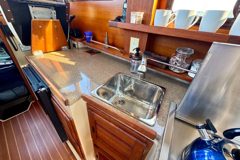 Slide: The Image of Cozy Ranger 27 boat kitchen with sink, countertop, and wooden cabinetry, 2012 model. - 34