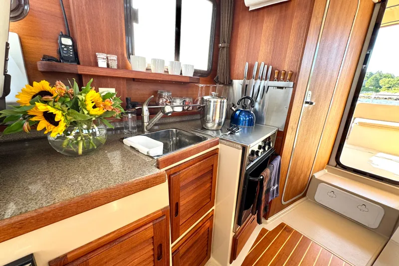 Slide: The Image of Cozy Ranger 27 boat kitchen with wooden cabinets, sunflowers, and modern appliances. - 35