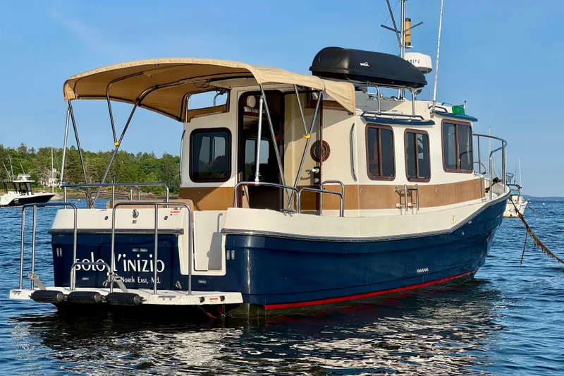 Slide: The Image of 2012 Ranger 27 boat with canopy, docked on calm water, surrounded by trees. - 4