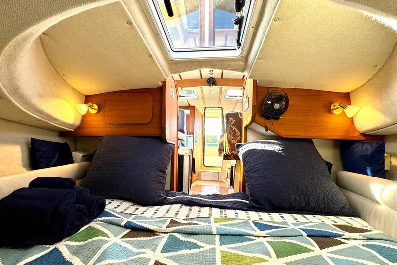 Slide: The Image of Cozy interior of 2012 Ranger 27 boat with bed, pillows, and wooden accents. - 49