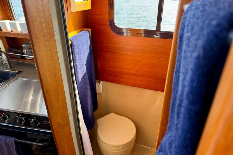 Slide: The Image of Compact bathroom in 2012 Ranger 27 boat with wooden interior and blue towels. - 55