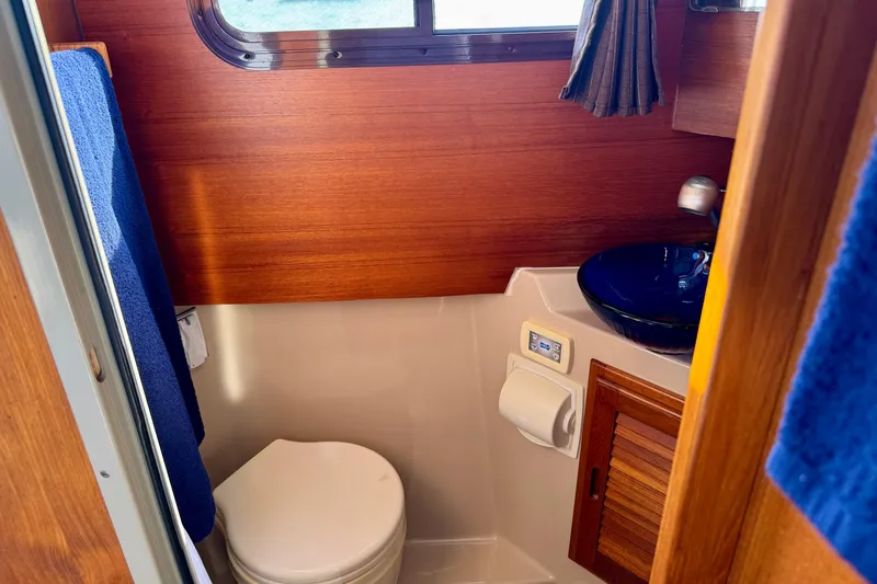 Slide: The Image of Compact bathroom in 2012 Ranger 27 boat with wooden paneling and blue accents. - 56