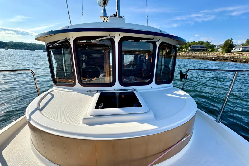 Slide: The Image of 2012 Ranger 27 boat on water, featuring cabin windows and scenic shoreline view. - 7