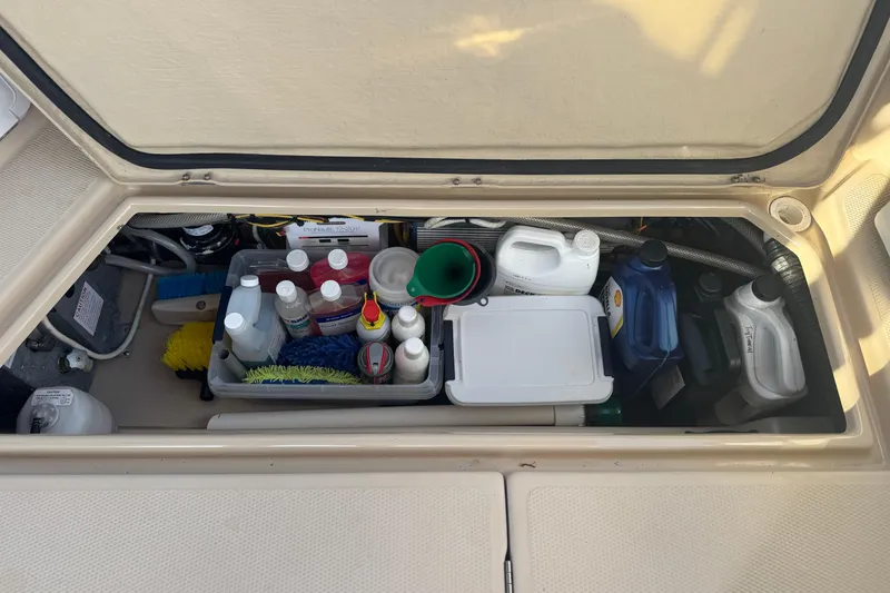 Slide: The Image of Storage compartment in a 2012 Ranger 27 boat, filled with cleaning supplies and maintenance items. - 71