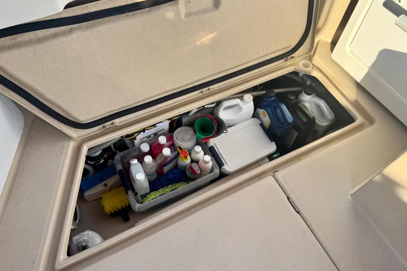 Slide: The Image of Storage compartment on 2012 Ranger 27 boat, filled with cleaning supplies and maintenance items. - 72