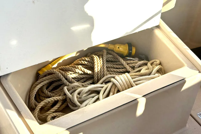 Slide: The Image of Storage compartment on a 2012 Ranger 27 boat with coiled ropes and a yellow cable. - 74