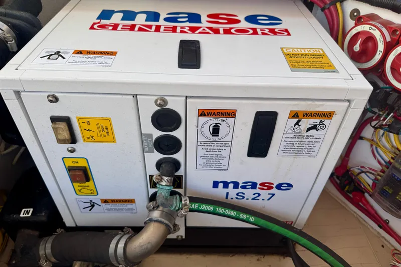 Slide: The Image of Mase I.S.2.7 generator with warning labels, installed in a Ranger 27, 2012 model. - 79