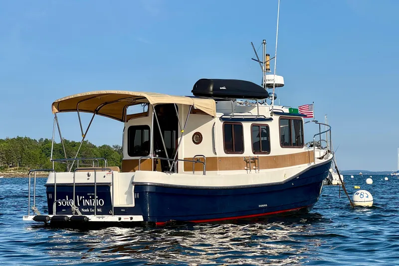 Slide: The Image of 2012 Ranger 27 boat anchored on calm water with canopy and American flag. - 93