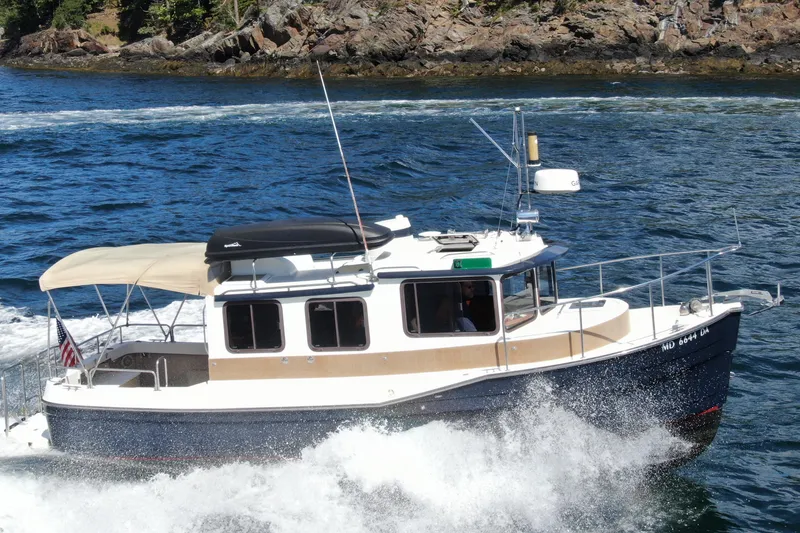 Slide: The Image of 2012 Ranger Tugs R-27 cruising on a scenic waterway with rocky shoreline. - 96