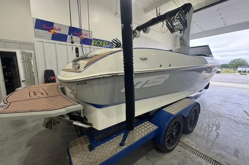 Slide: The Image of 2019 MB F22 Tomcat boat on trailer in garage, featuring sleek design and Red Bull banners. - 2