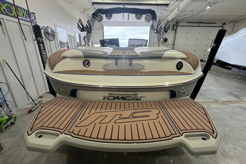 Slide: The Image of 2019 MB F22 Tomcat boat in garage, featuring teak-style decking and wakeboard equipment. - 4