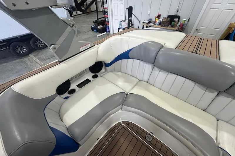 Slide: The Image of 2019 MB F22 Tomcat boat interior with gray and white seating, wood accents, and speakers. - 6