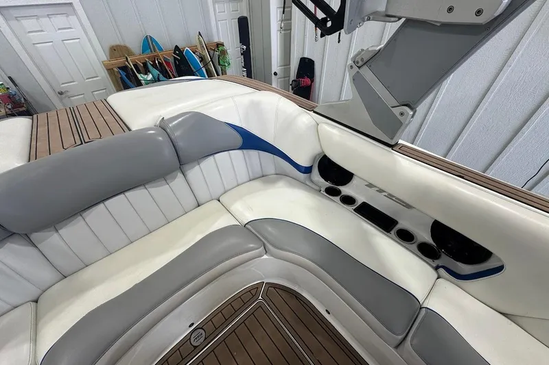 Slide: The Image of 2019 MB F22 Tomcat boat interior with white and gray seating, wood accents, and speakers. - 7