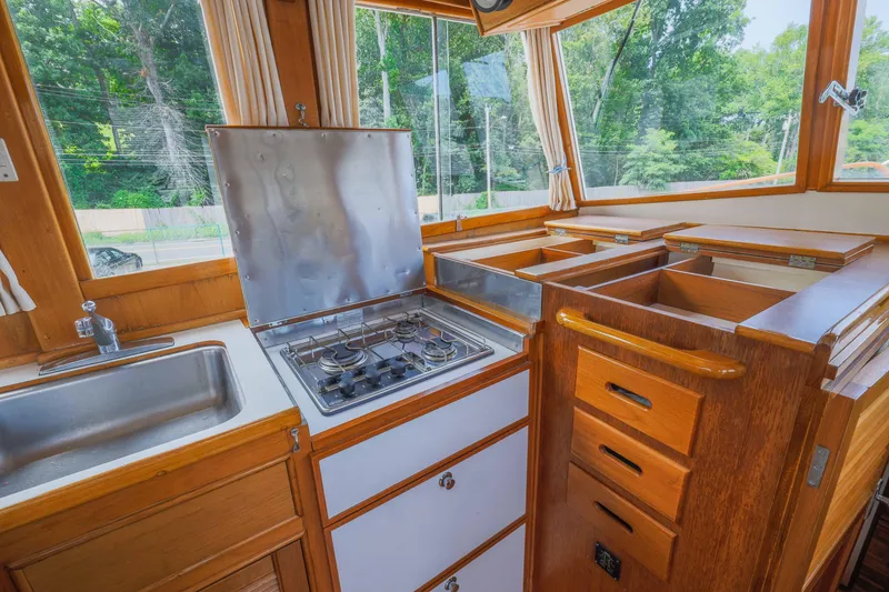 Slide: The Image of 1988 Grand Banks 36 Sedan kitchen with stove, sink, and wooden cabinetry, surrounded by windows. - 14