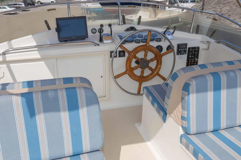 Slide: The Image of 1988 Grand Banks 36 Sedan helm with wooden wheel and striped seating. - 2