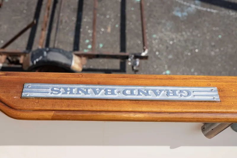 Slide: The Image of 1988 Grand Banks 36 Sedan boat nameplate on wooden railing. - 26