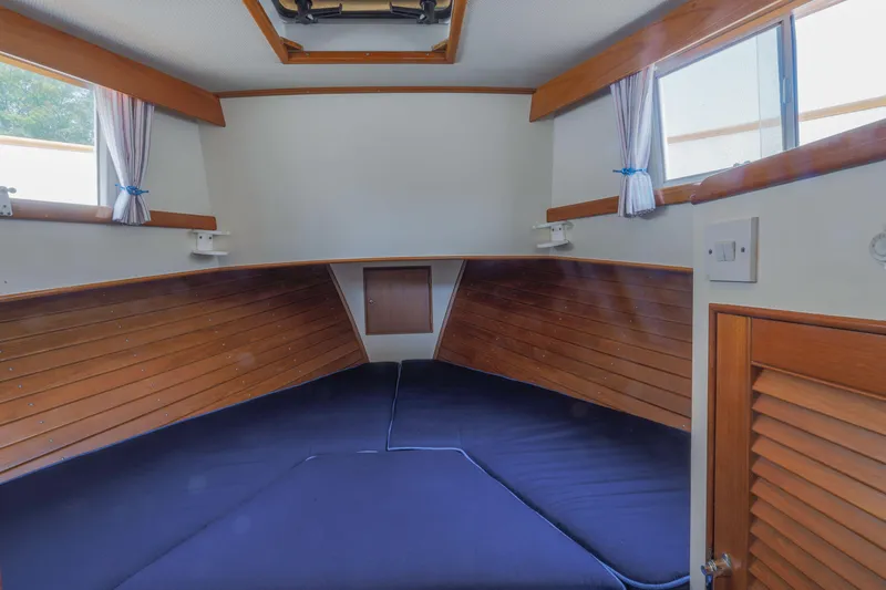Slide: The Image of 1988 Grand Banks 36 Sedan cabin interior with wood paneling and blue bedding. - 5