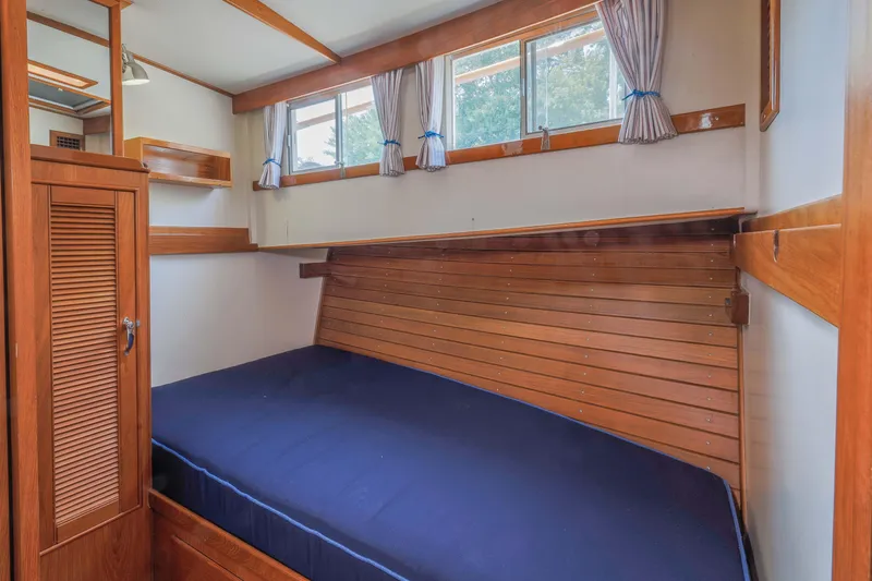 Slide: The Image of 1988 Grand Banks 36 Sedan cabin interior with wooden paneling and blue bedding. - 6