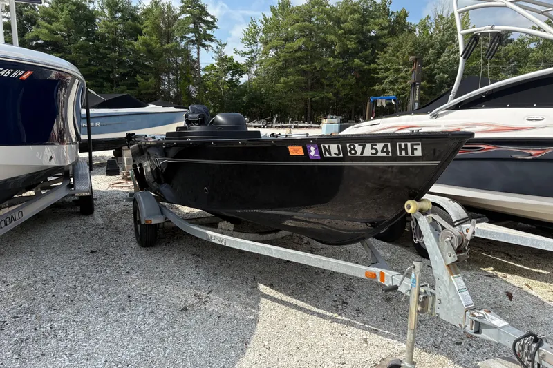 Slide: The Image of 2015 Lund 1650 Rebel XL Sport boat on trailer, parked among other boats. - 1