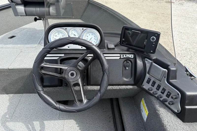 Slide: The Image of 2015 Lund 1650 Rebel XL Sport boat dashboard with steering wheel and control panel. - 13