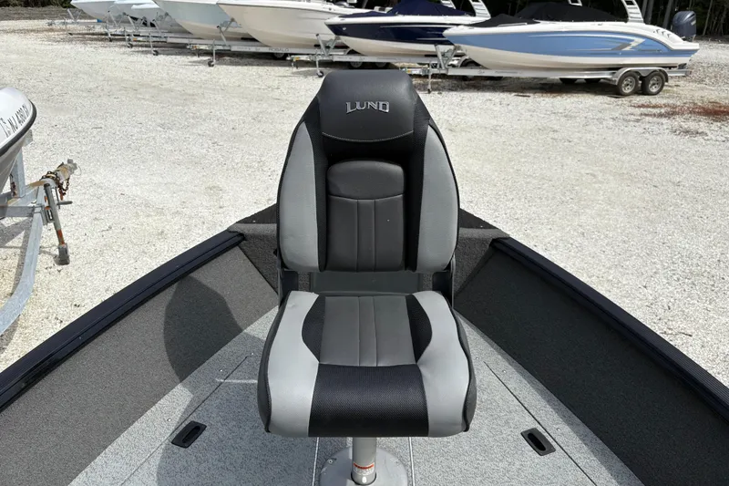 Slide: The Image of 2015 Lund 1650 Rebel XL Sport boat seat, gray and black, in a gravel lot with other boats. - 15