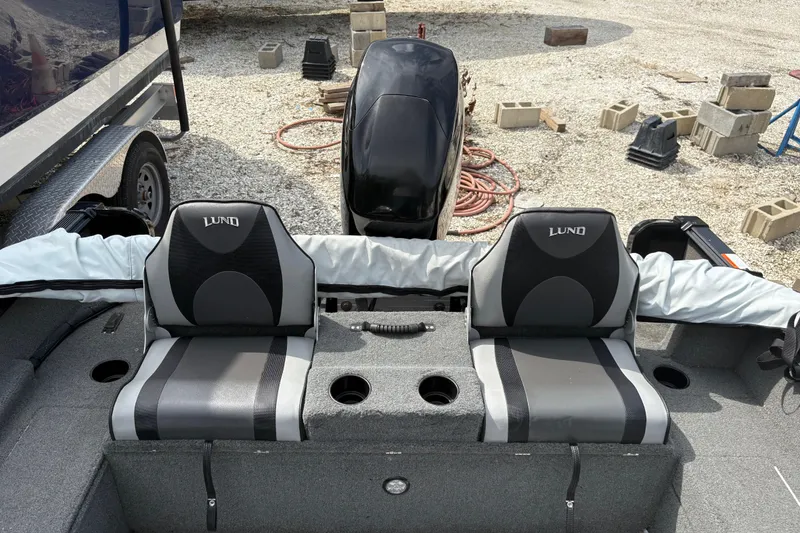 Slide: The Image of 2015 Lund 1650 Rebel XL Sport boat interior with dual seats and motor, surrounded by gravel. - 7