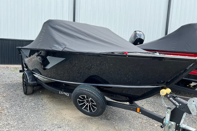The Image of 2025 Lund 1775 Adventure Sport boat with cover on trailer, parked outdoors. - 1