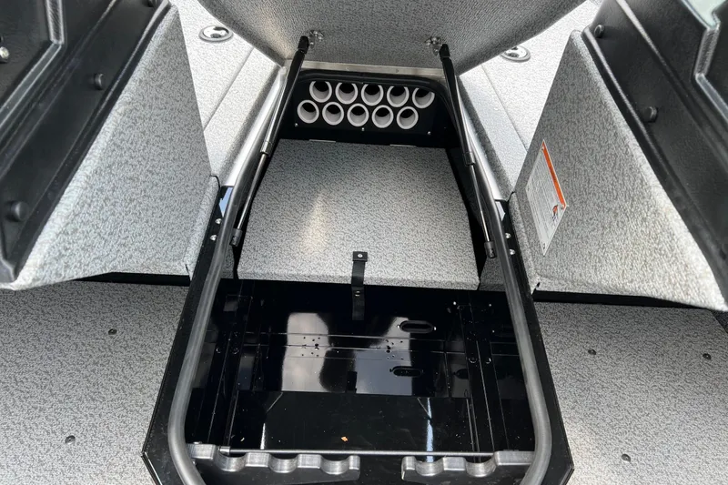 Slide: The Image of 2025 Lund 1775 Adventure Sport boat storage compartment with rod holders and carpeted interior. - 16