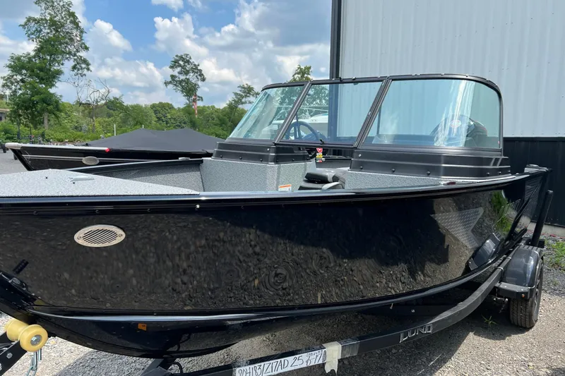 Slide: The Image of 2025 Lund 1775 Adventure Sport boat, black exterior, parked outdoors on a sunny day. - 8