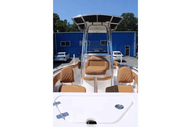 Slide: The Image of 2026 Key West 203 FS boat with tan seating and T-top, parked near blue building. - 8