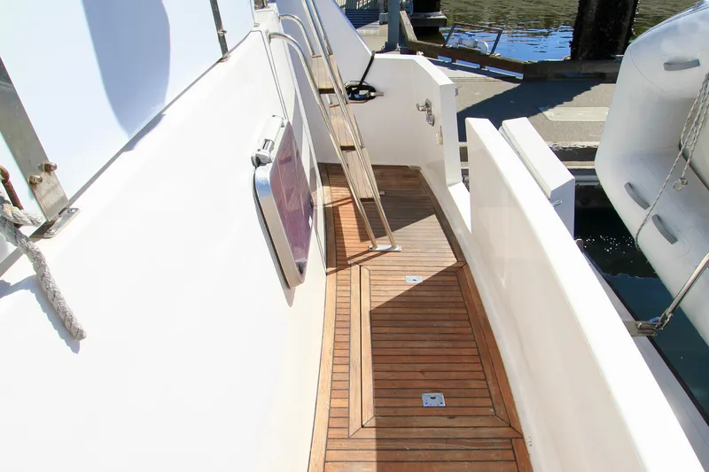Slide: The Image of 1987 Ocean Alexander 42 yacht with teak deck and white railing, docked by the water. - 16