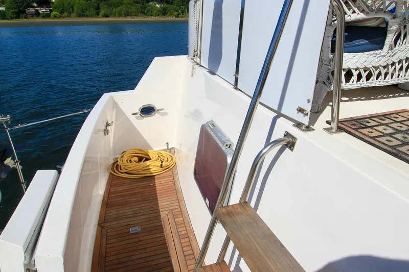 Slide: The Image of 1987 Ocean Alexander 42 yacht deck with wooden flooring and coiled yellow hose. - 17