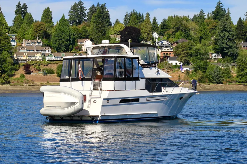 Slide: The Image of 1987 Ocean Alexander 42 yacht on serene water with scenic shoreline backdrop. - 2