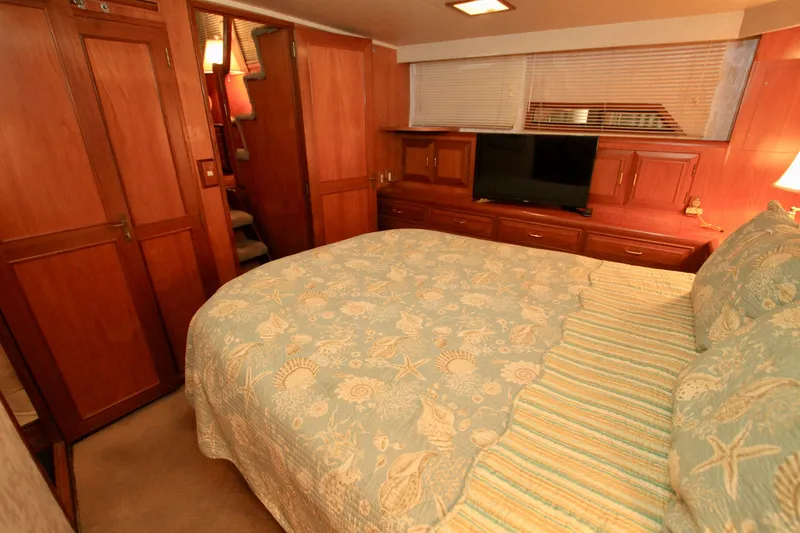 Slide: The Image of Luxurious bedroom interior of 1987 Ocean Alexander 42 yacht with wood paneling and cozy bedding. - 58
