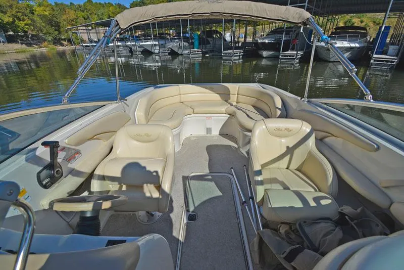 Slide: The Image of 2000 Sea Ray 260 Bow Rider interior with beige seating, docked at a marina. - 19