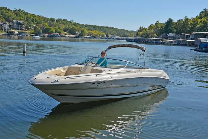 Slide: The Image of 2000 Sea Ray 260 Bow Rider on a serene lake with lush green surroundings. - 4