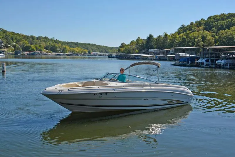 Slide: The Image of 2000 Sea Ray 260 Bow Rider on a serene lake with lush green surroundings. - 5