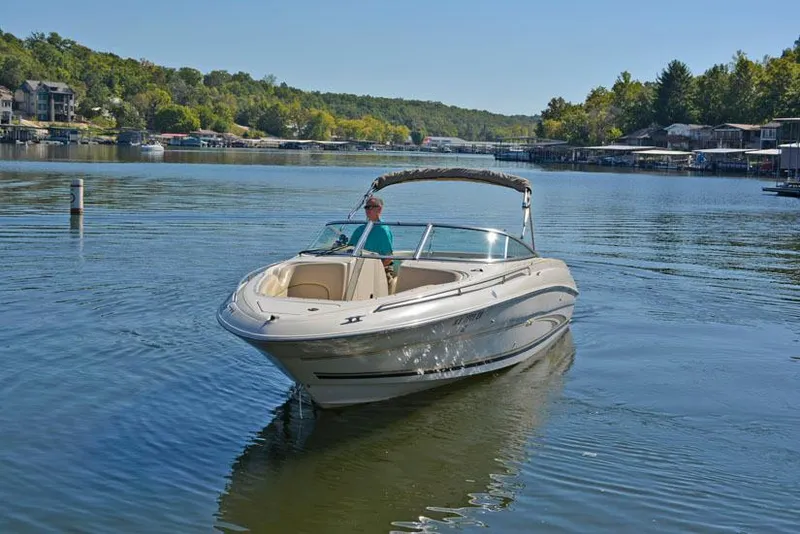 Slide: The Image of 2000 Sea Ray 260 Bow Rider cruising on a serene lake with lush green surroundings. - 6