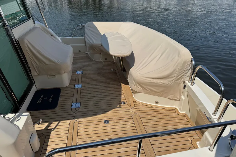 Slide: The Image of 2022 Sabre 48 Salon Express yacht deck with covered seating and wooden flooring. - 18