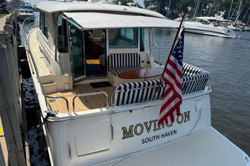 Slide: The Image of 2022 Sabre 48 Salon Express yacht docked, featuring striped seating and American flag. - 21