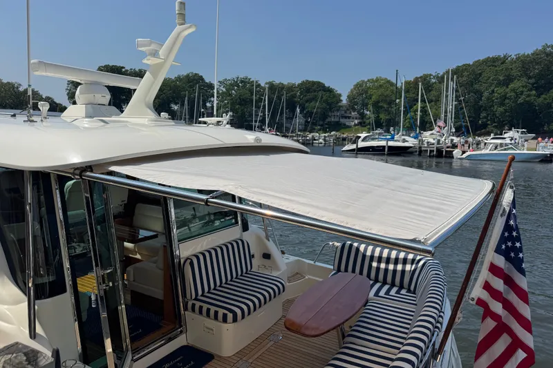 Slide: The Image of 2022 Sabre 48 Salon Express yacht with striped seating and American flag at marina. - 22